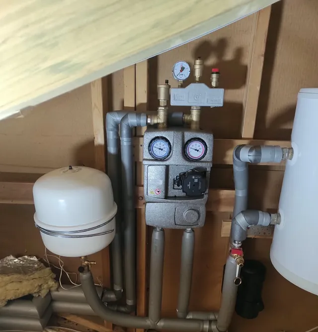 Pumpengruppe mit Vor- und Rücklaufthermometer, Sicherheitsgruppe und Membran-Ausdehnungsgefäß an der Holzständerwand