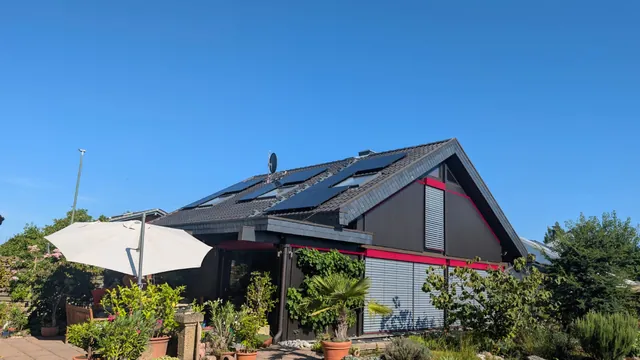 Fertige Photovoltaikanlage auf dem Satteldach eines Einfamilienhauses, vom Garten aus gesehen