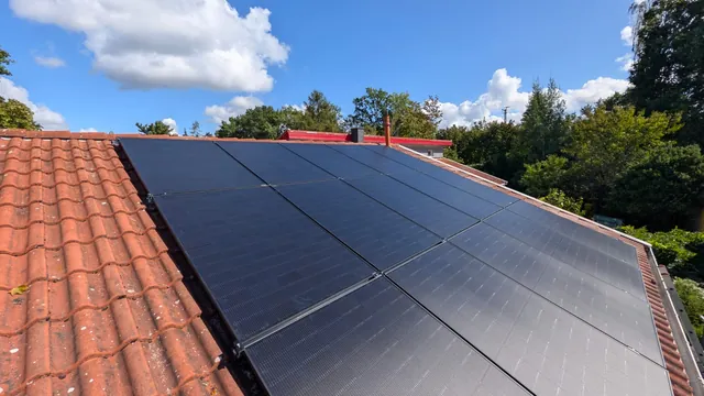 Photovoltaikanlage mit schwarzen Modulen auf einem roten Ziegeldach, vom First aus gesehen