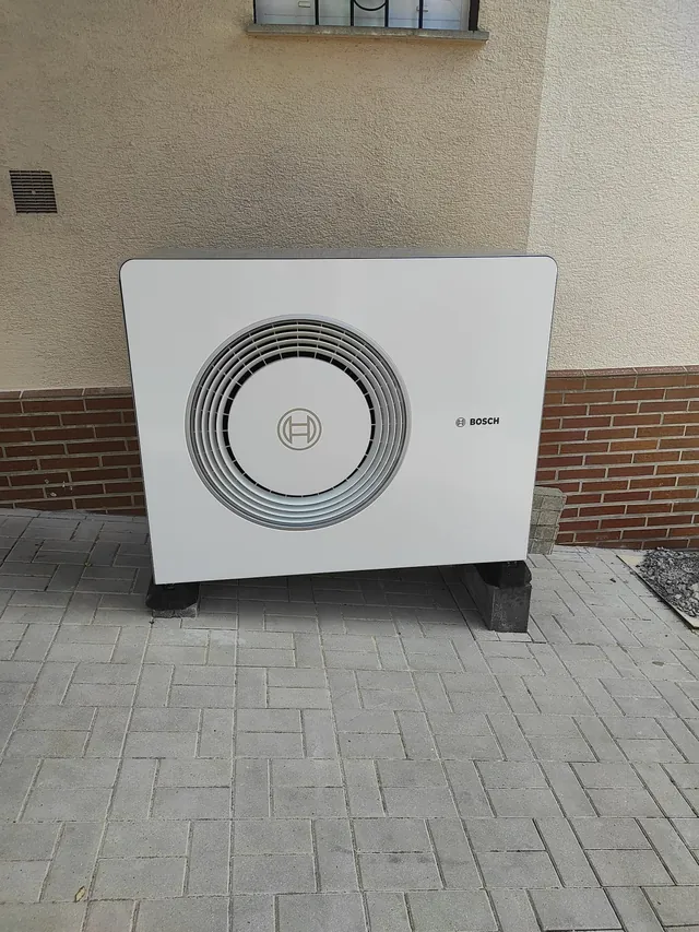 Wärmepumpen-Außeneinheit auf Gummifüßen vor der Hauswand aufgestellt