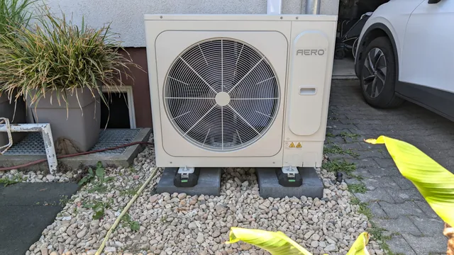 Wärmepumpen-Außeneinheit auf Gehwegplatten im Garten, mit Abstand zur Hauswand